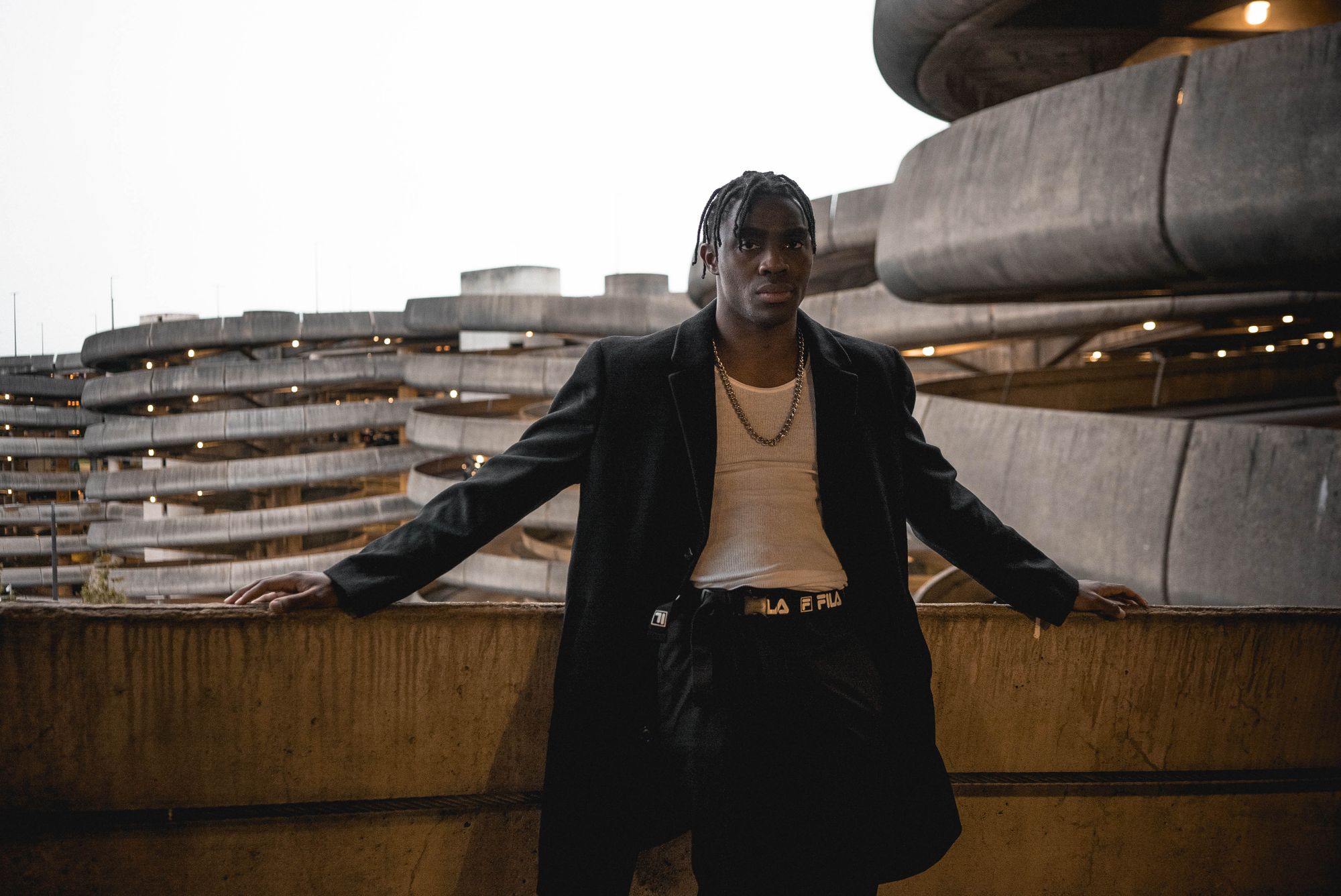 Streetwear in the city: black outerwear against brutalist concrete